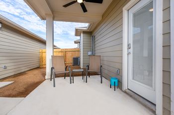 A patio with a table and chairs and a ceiling fan.